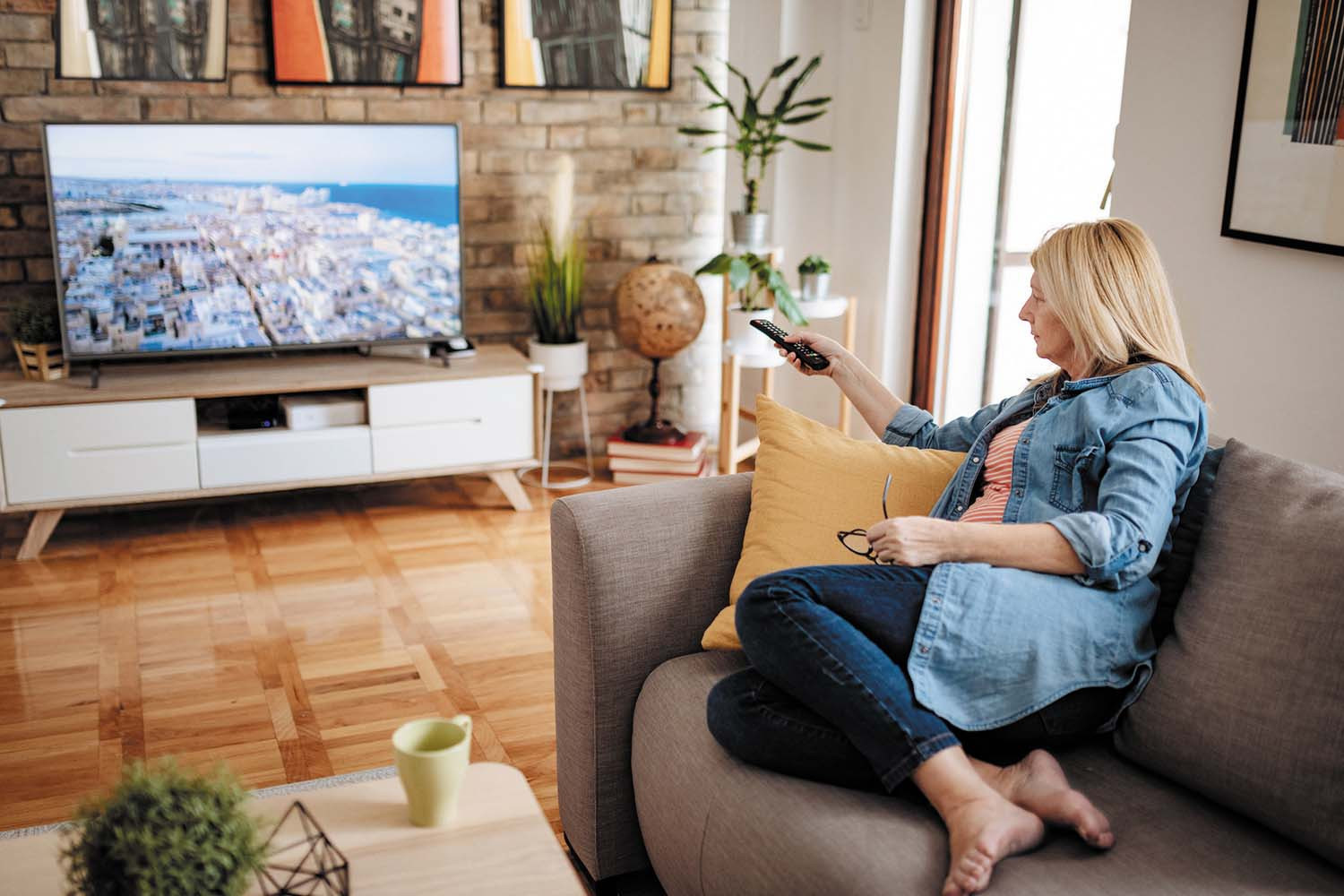 Woman watching television with remote in hand