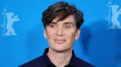 Getty Images Cillian Murphy wearing a navy shirt smiling against a blue backdrop