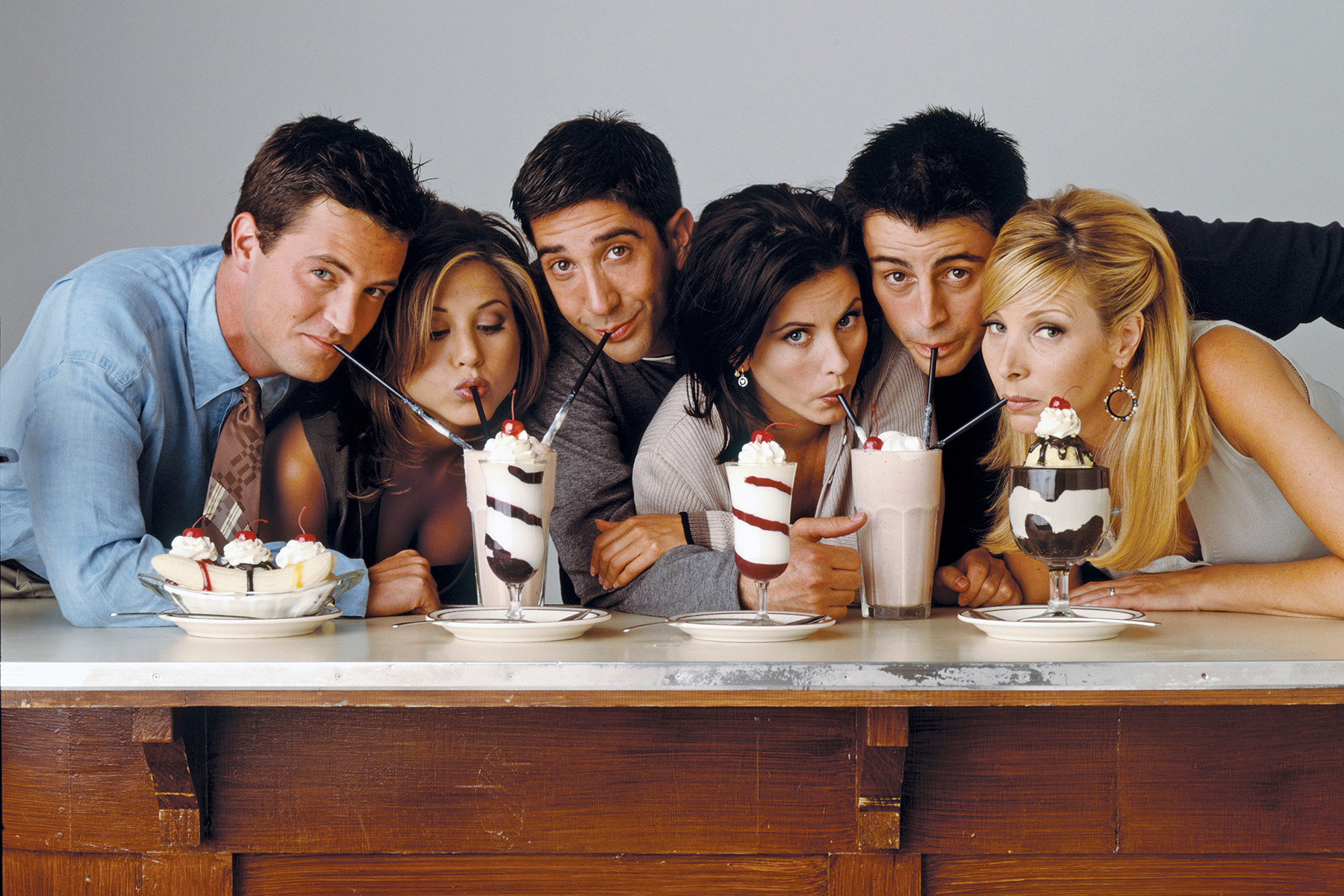 alt text: The cast of Friends sitting on the iconic orange couch in Central Perk.