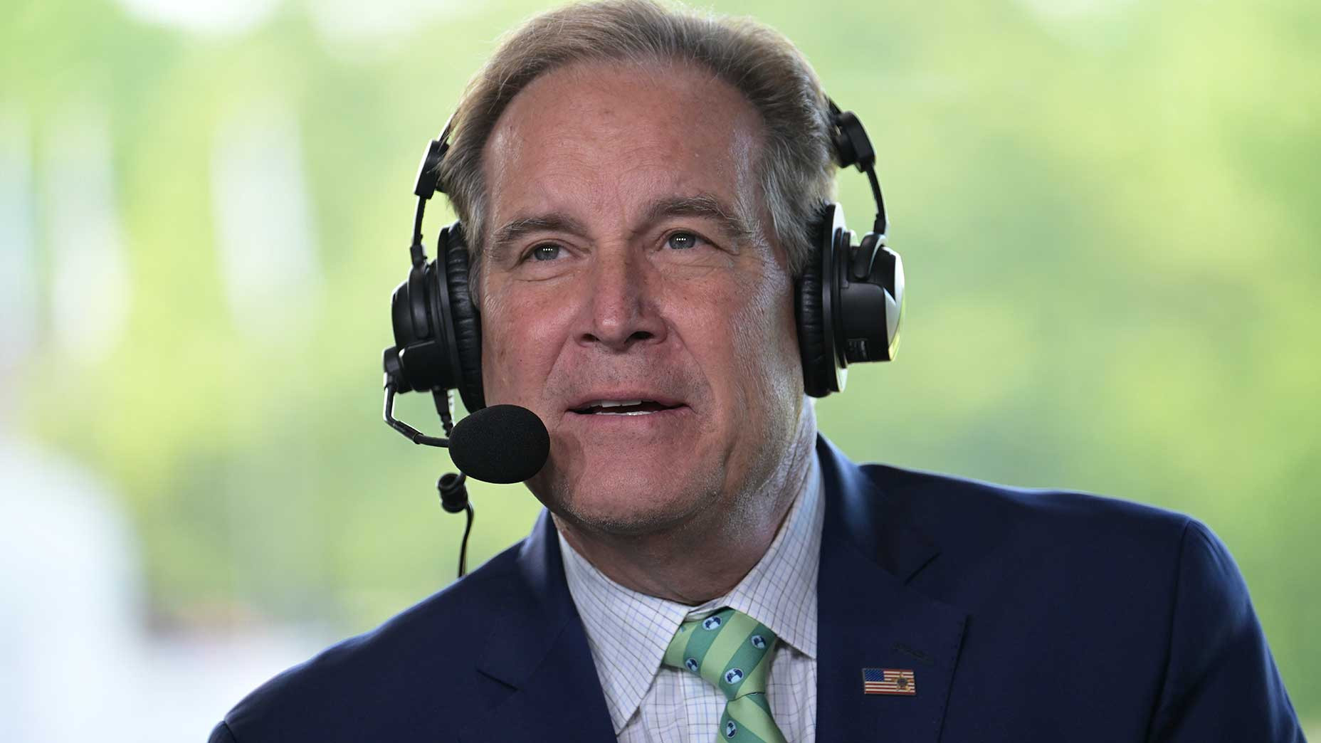 Jim Nantz speaks into a headset at a golf tournament.