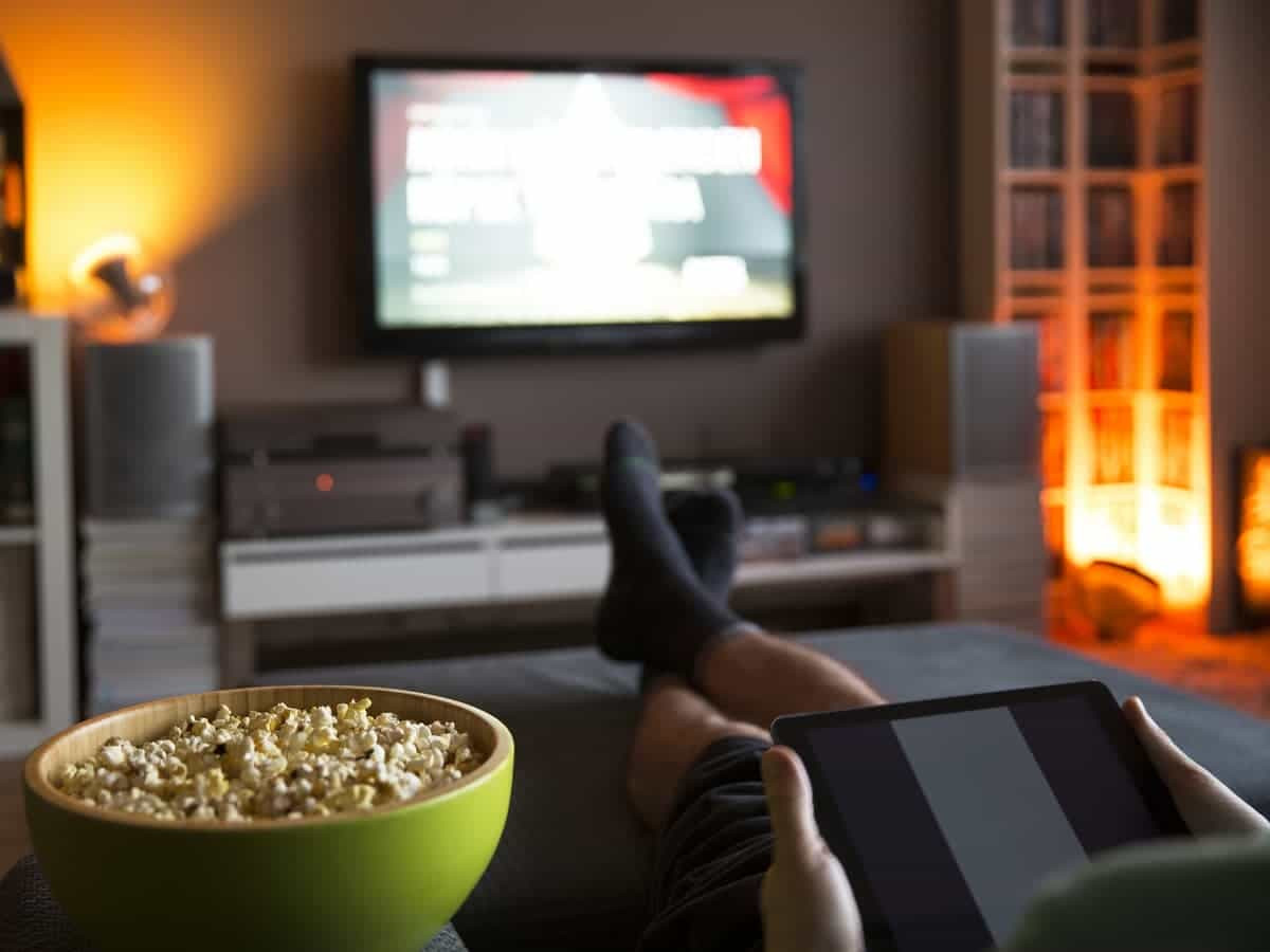 Person watching television with a bowl of popcorn.