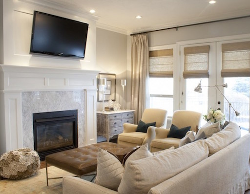 TV high above the fireplace in this cream living room